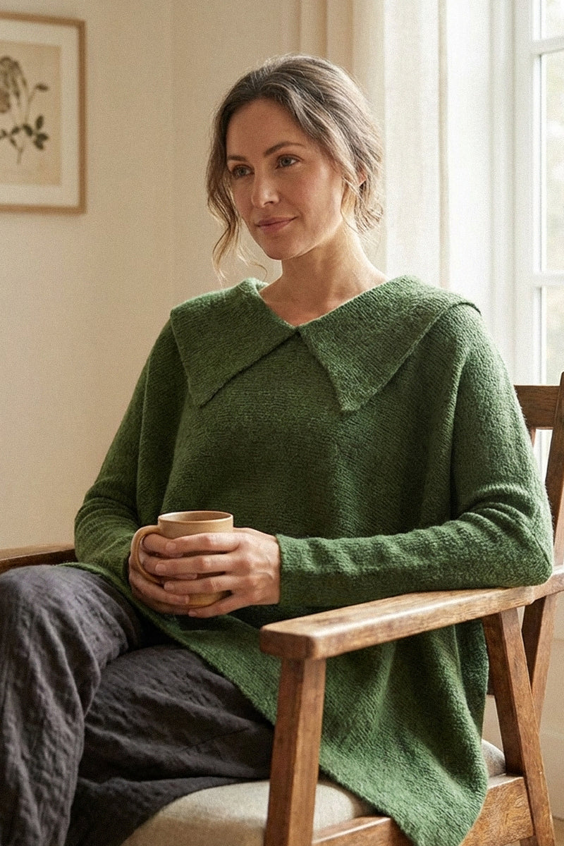 Woman wearing a green sweater sitting in a chair holding a cup.